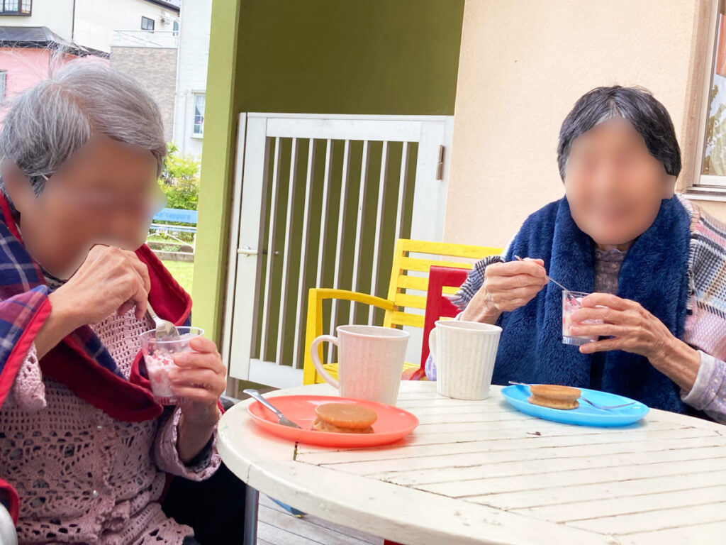 特別養護老人ホーム　ル・リアンふかみの1階ウッドデッキで、4月28日のおやつを楽しむ2名のご利用者様です。