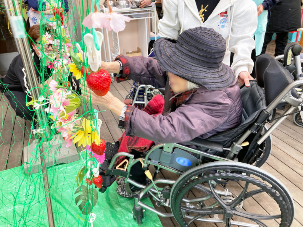 特別養護老人ホーム　ル・リアンふかみの1階ウッドデッキで、いちご狩りレクリエーションを楽しむご利用者様です。