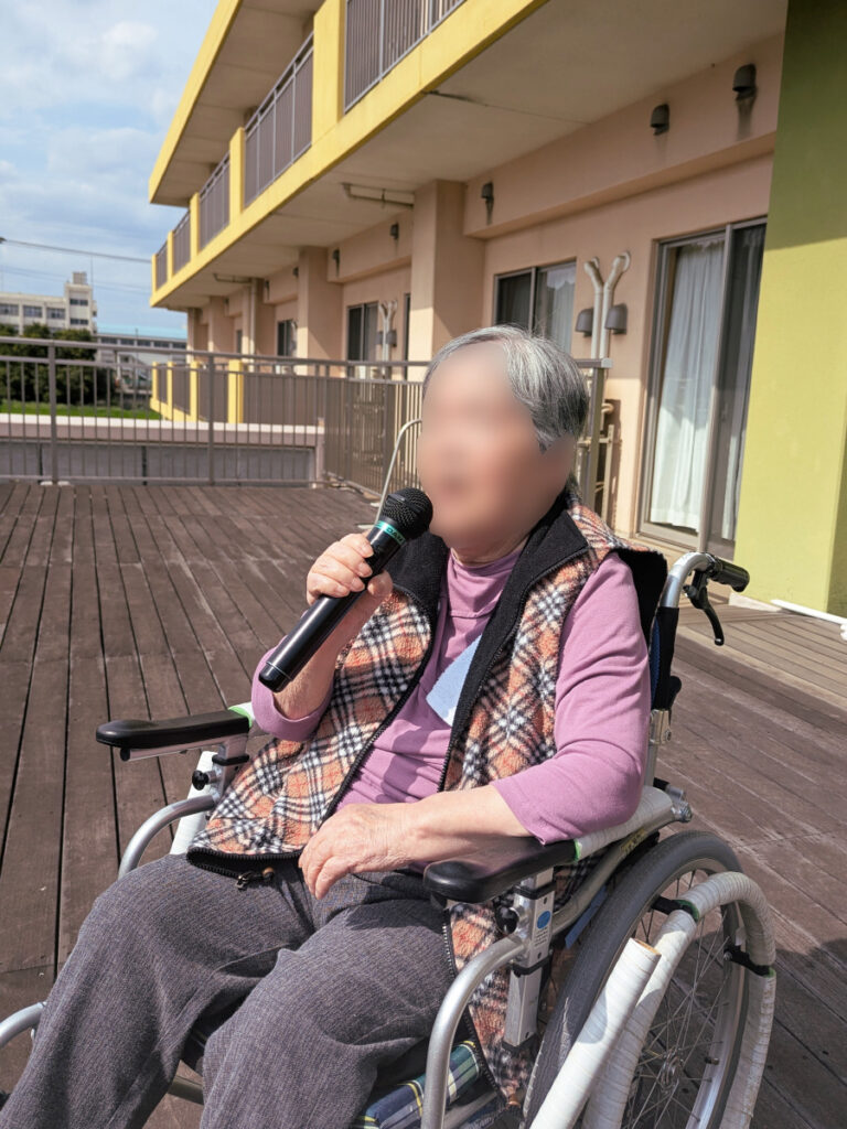 特別養護老人ホーム　ル・リアンふかみ2階のウッドデッキにて、青空カラオケを楽しむご利用者様。