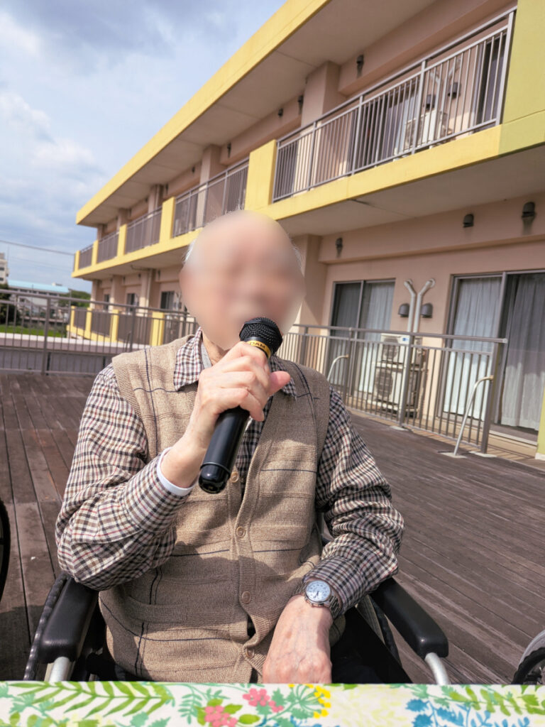 特別養護老人ホーム　ル・リアンふかみ2階のウッドデッキにて、青空カラオケを楽しむご利用者様。