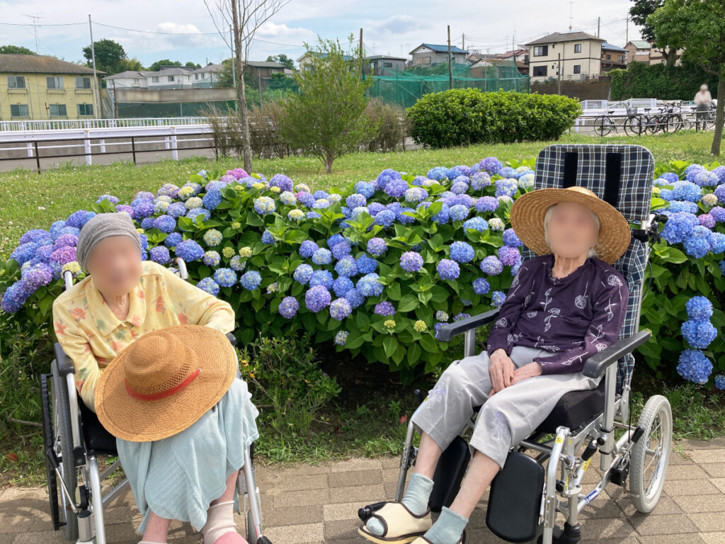 特別養護老人ホーム ル・リアンふかみの外出レクリエーションの様子です。瀬谷本郷公園の園内に咲いたあじさいの前で、ご利用者様2名の記念撮影をした写真です。