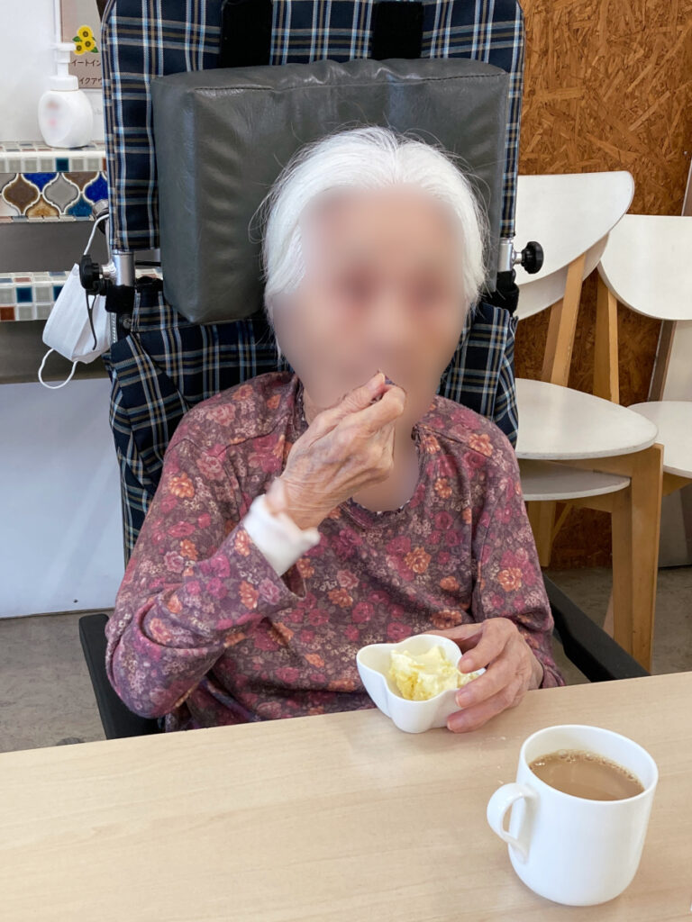 特別養護老人ホーム　ル・リアンふかみの外出レクリエーションの様子です。カフェの席で、バニラアイスをほおばるご利用者様です。