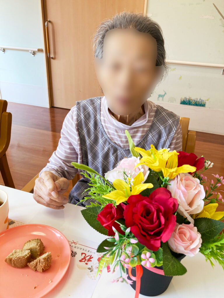 特別養護老人ホーム ル・リアンふかみの、令和8年9月17日(木)のおやつの様子です。お花が飾られたテーブルで、紅茶ケーキを召し上がるご利用者様です。