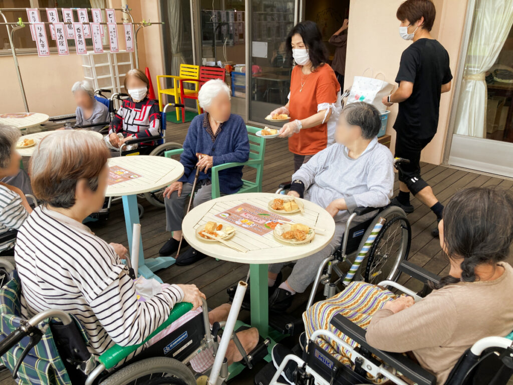 特別養護老人ホーム ル・リアンふかみで、令和8年9月22日(火)の午後に開催した「居酒屋レクリエーション」の様子です!みなさまに、リクエストの乾杯ドリンクとおつまみをお配りします。