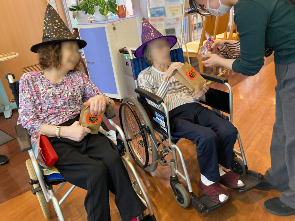 特別養護老人ホーム ル・リアンふかみで、令和8年10月13日(火)に行った「ハロウィンレクリエーション」の様子です。魔法使いの帽子で仮装したご利用者様に、お菓子をプレゼント。